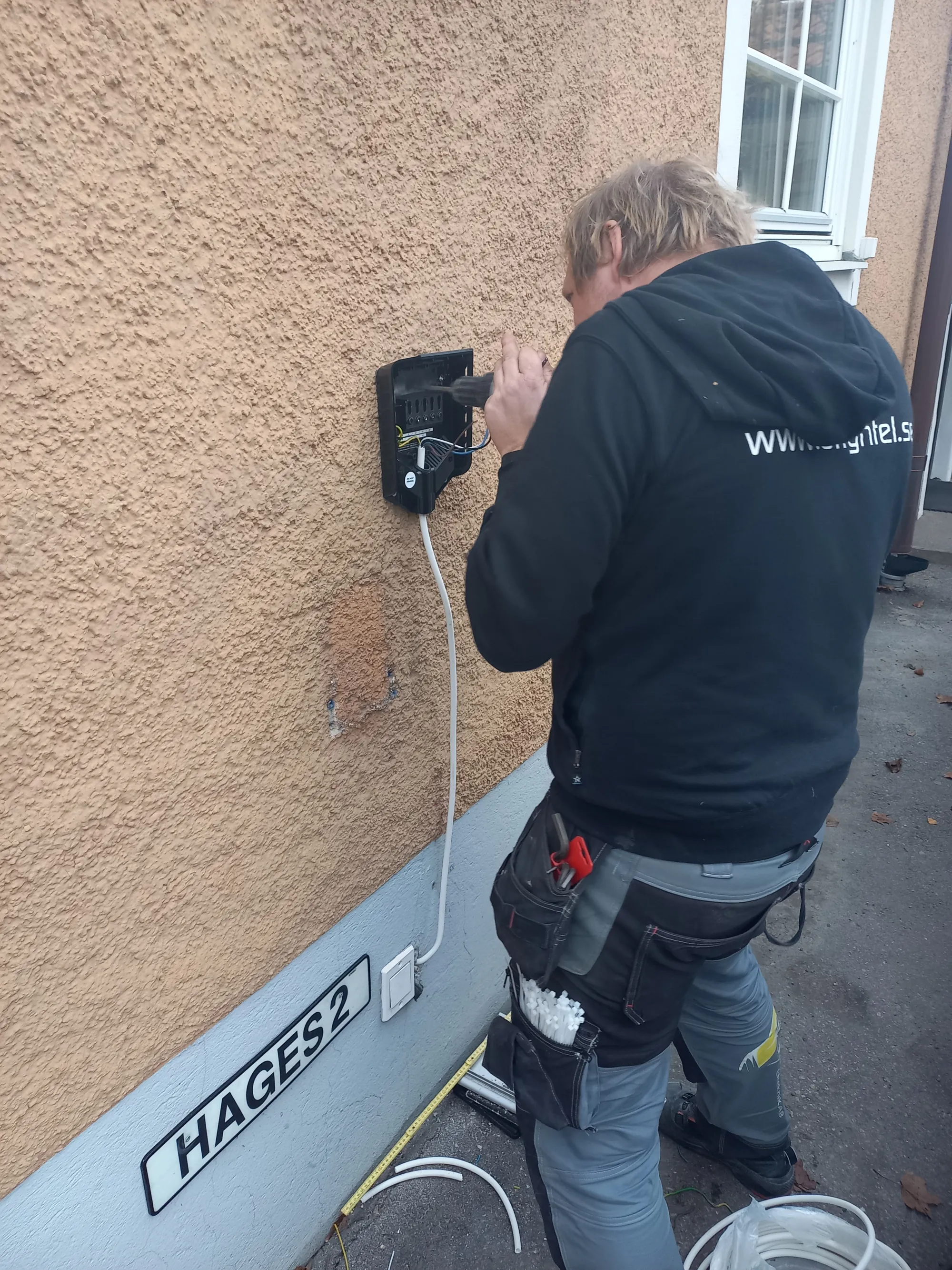 Elektriker installerar laddbox på husfasad